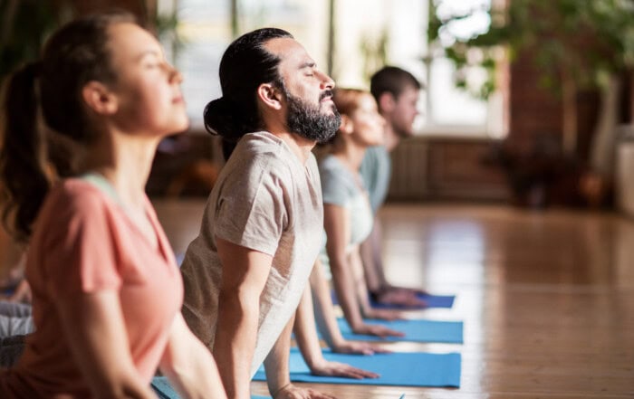Eine Gruppe von Menschen in einem Yogaraum praktiziert Yoga für Hormonbalance