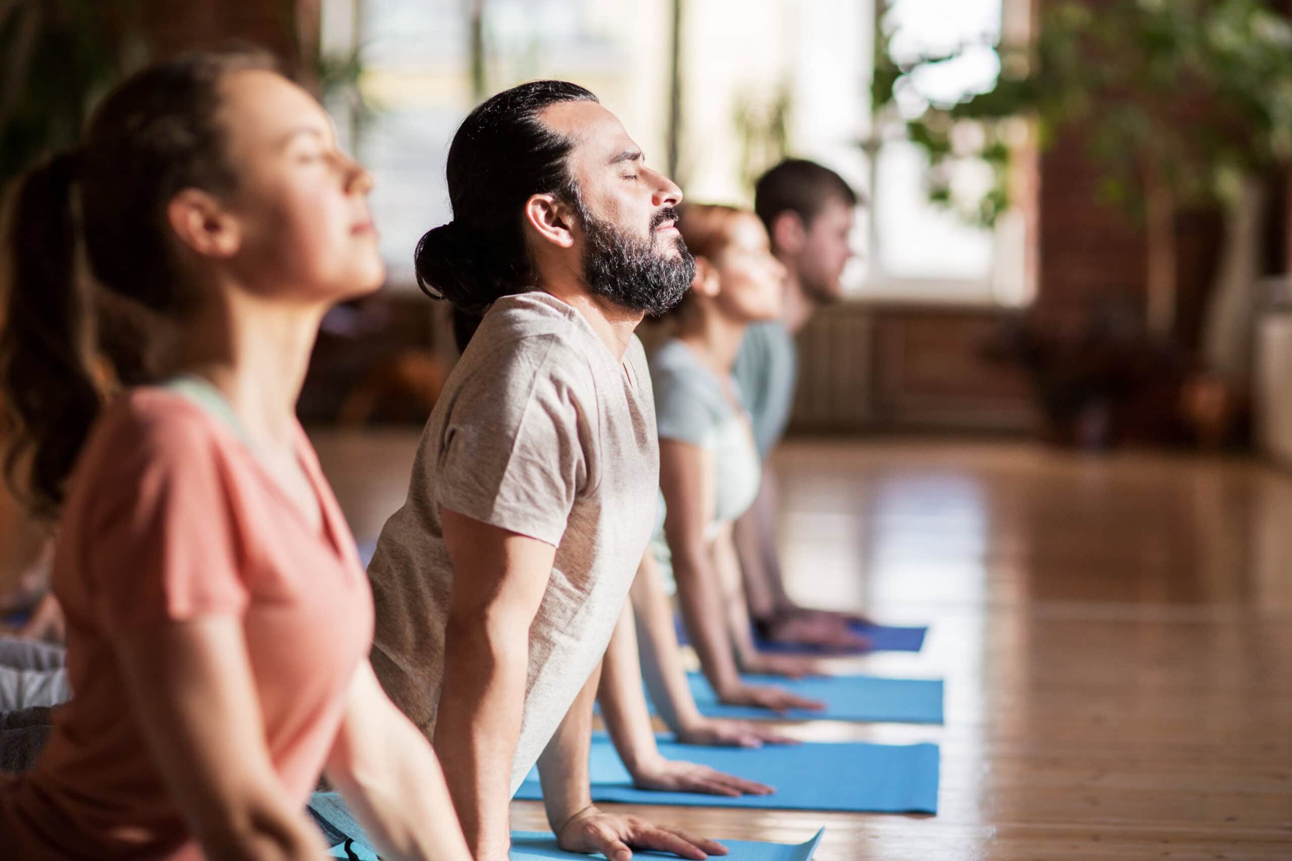 Eine Gruppe von Menschen in einem Yogaraum praktiziert Yoga für Hormonbalance
